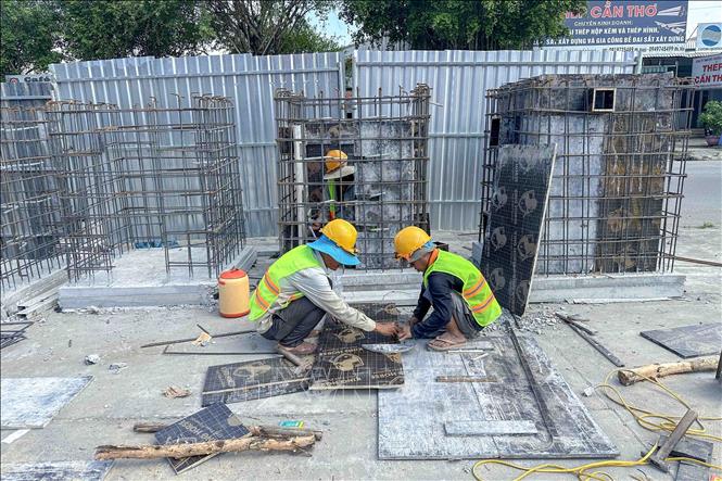 Công nhân thi công các cấu kiện đúc sẵn của hệ thống thoát nước dự án mở rộng Quốc lộ 91. Ảnh: Thanh Liêm - TTXVN