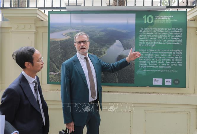 Đại sứ Pháp tại Việt Nam Olivier Brochet giới thiệu bộ ảnh kỷ niệm 10 năm Hiệp định Paris với du khách. Ảnh: Phan Phương – TTXVN