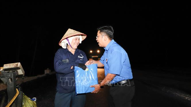Anh Trần Việt Tuấn, Phó Bí thư Thành đoàn Cần Thơ trao quà đến công nhân thi công ca đêm. Ảnh: Hồng Thái - TTXVN