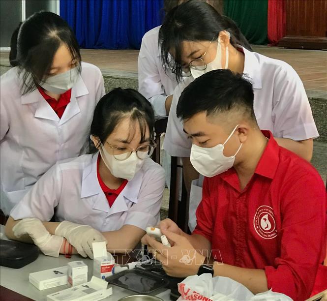 Anh Phạm Tuấn Vũ trao đổi công tác hiến máu với các bạn trẻ. Ảnh: TTXVN phát