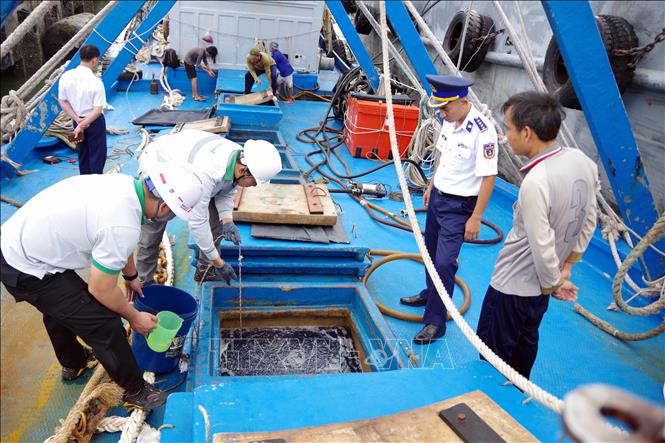 Lực lượng chức năng khiểm tra, lấy mẫu dầu từ tàu để đưa đi giám định. Ảnh: TTXVN phát  