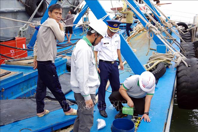 Lực lượng chức năng niêm phong mẫu dầu để đưa đi giám định. Ảnh: TTXVN phát