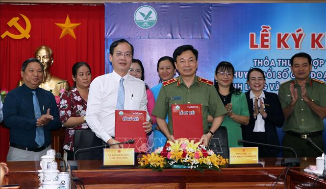 Chủ tịch UBND tỉnh Vĩnh Long Trần Trí Quang và Thiếu tướng Trương Sơn Lâm, Chủ tịch Tổng Công ty Viễn thông MobiFone trao thỏa thuận hợp tác.  Ảnh: Phạm Minh Tuấn-TTXVN.