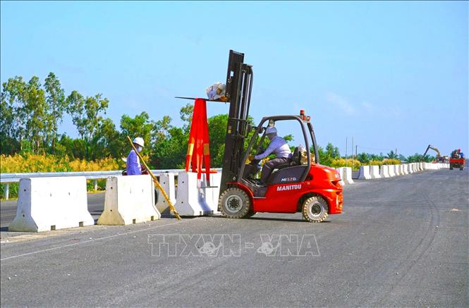 Các công nhân đang lắp dải phân cách, hoàn thiện những bước cuối để kịp thông xe kỹ thuật. Ảnh: Huỳnh Anh - TTXVN