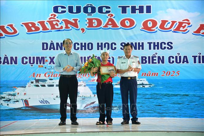 Đại tá Nguyễn Thái Dương, Uỷ viên Ban Thường vụ Đảng uỷ, Phó Chính uỷ Bộ Tư lệnh Vùng Cảnh sát biển 4 và đại diện Sở Giáo dục - Đào tạo An Giang trao giải nhất cho Em Trần Đăng Tiến, học sinh lớp 6A4, Trường THCS & THPT Võ Văn Kiệt. Ảnh: TTXVN phát