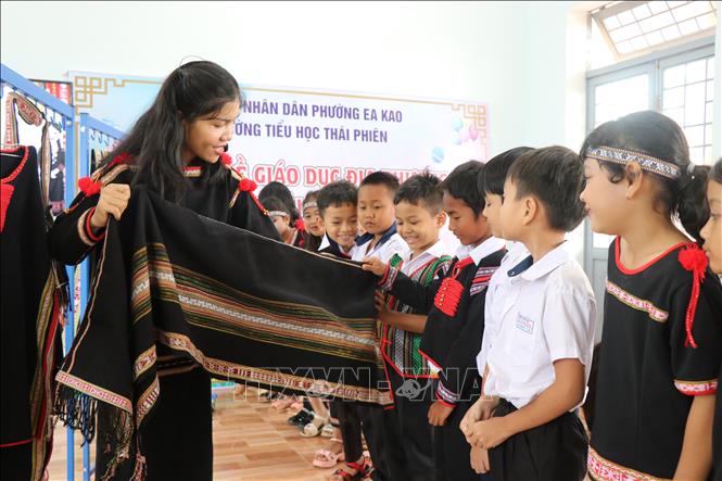 Học sinh Trường Tiểu học Thái Phiên (phường Ea Kao) tìm hiểu sản phẩm dệt thổ cẩm của đồng bào người Ê Đê. Ảnh: Tường Quân - TTXVN 