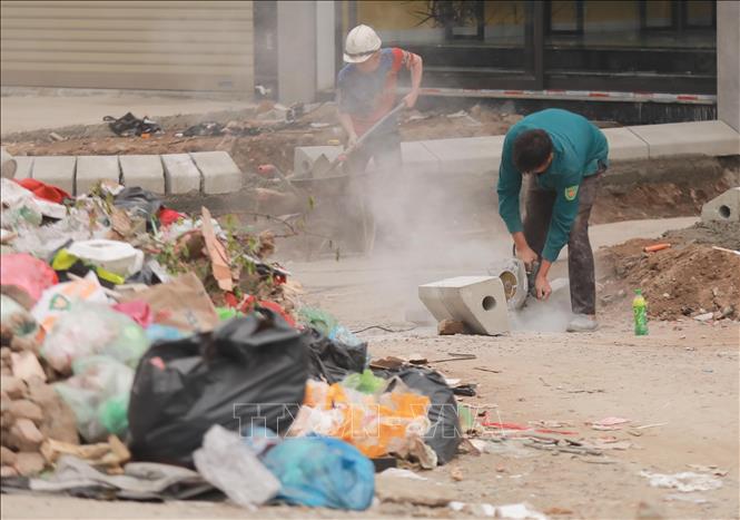 Công nhân cắt gạch, đá thi công vỉa hè trên địa bàn Hà Nội, không che chắn, khiến bụi mù phát tán, ảnh hưởng môi trường và sinh hoạt người dân. Ảnh: Phan Phương – TTXVN