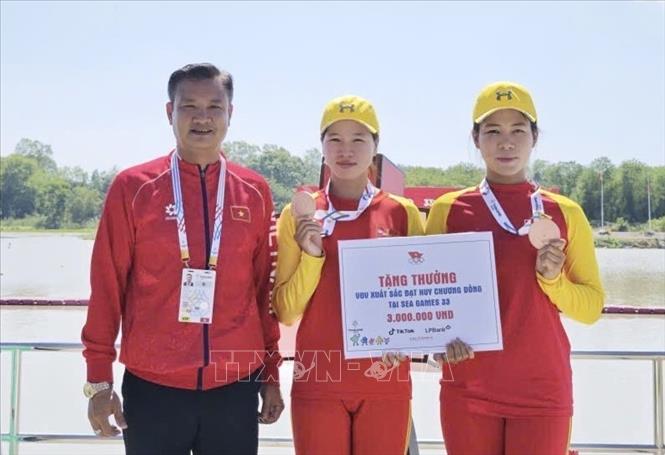 Lãnh đạo đoàn Thể thao Việt Nam trao thưởng, động viên các VĐV Nguyễn Thị Vân Anh, Phạm Thị Bích Ngọc giành HCĐ thuyền đôi nữ. Ảnh: TTXVN phát