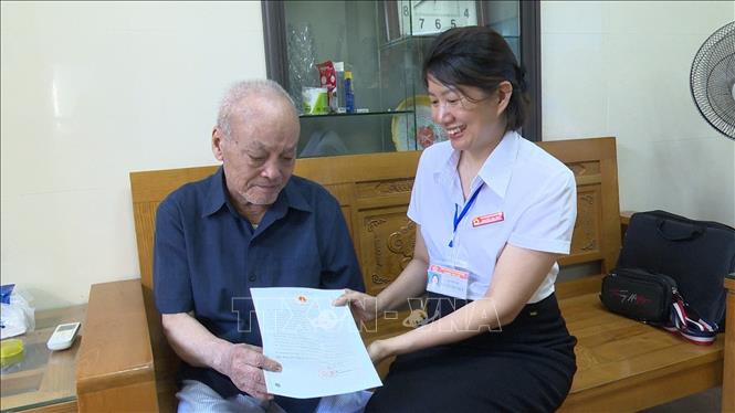 Cụ Hoàng Văn Sợi nhận lại giấy khai sinh được cấp lại tại nhà. Ảnh: Tiến Vĩnh – TTXVN 