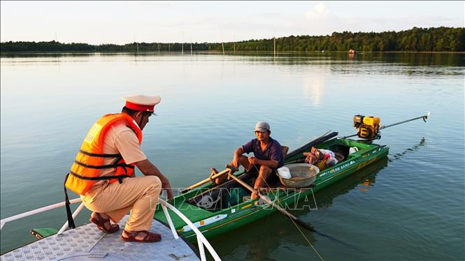 Cảnh sát giao thông Công an tỉnh Tây Ninh, tuyên truyền phổ biến các kiến thức pháp luật về an toàn giao thông thủy cho người dân đánh bắt thủy sản trên hồ Dầu Tiếng. Ảnh: Minh Phú - TTXVN