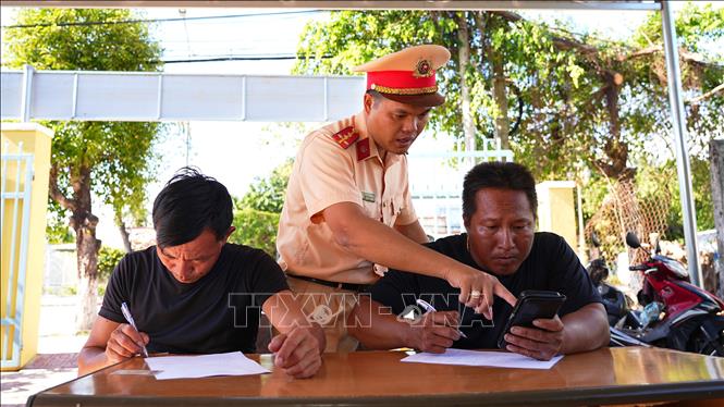 Cán bộ Đội Cảnh sát giao thông đường thuỷ số 1, Phòng Cảnh sát giao thông Công an tỉnh Tây Ninh hướng dẫn người dân, chủ phương tiện hoạt động trên lưu vực hồ Dầu Tiếng ký cam kết chấp hành pháp luật về an toàn giao thông. Ảnh: Minh Phú - TTXVN