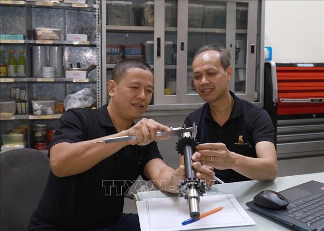 Kỹ sư Nguyễn Duy Khuê (bên phải) trao đổi với đồng nghiệp về chế tạo chi tiết máy. Ảnh: Xuân Triệu - TTXVN