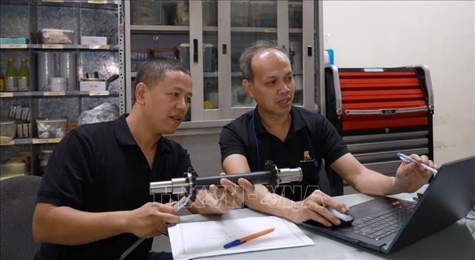 Kỹ sư Nguyễn Duy Khuê trao đổi với đồng nghiệp về chế tạo chi tiết máy. Ảnh: Xuân Triệu - TTXVN