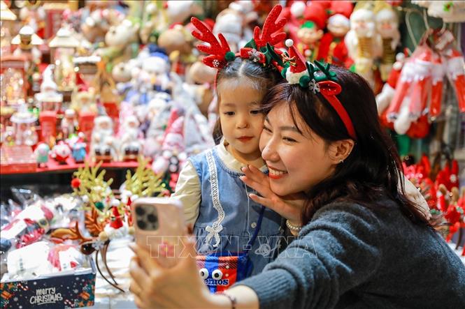 Người dân lưu lại khoảnh khắc trước Giáng sinh tại phố Hàng Mã (phường Hoàn Kiếm). Ảnh: Khánh Hoà - TTXVN