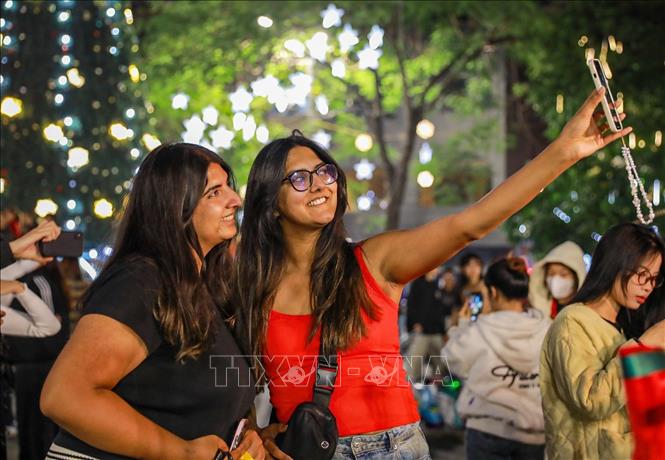 Người dân và du khách lưu lại khoảnh khắc trước Giáng sinh tại Nhà thờ lớn (phường Hoàn Kiếm). Ảnh: Khánh Hoà - TTXVN