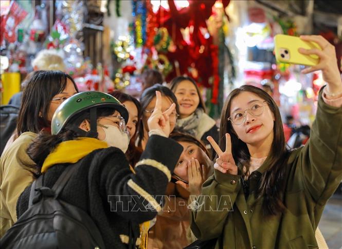 Người dân lưu lại khoảnh khắc trước Giáng sinh tại phố Hàng Mã (phường Hoàn Kiếm). Ảnh: Khánh Hoà - TTXVN