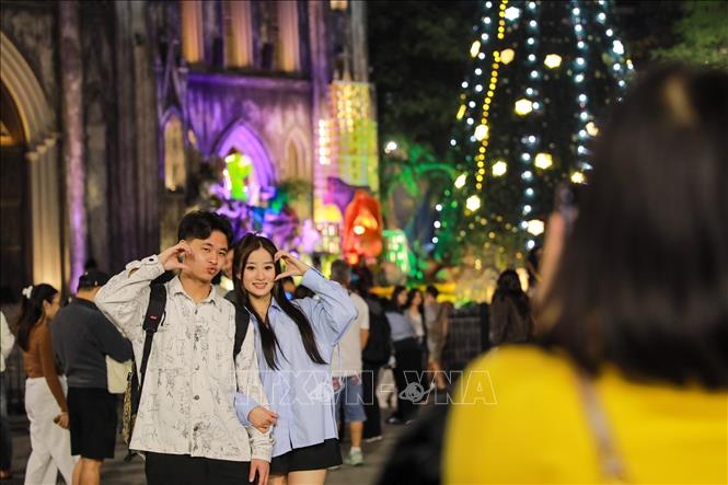 Người dân và du khách lưu lại khoảnh khắc trước Giáng sinh tại Nhà thờ lớn (phường Hoàn Kiếm). Ảnh: Khánh Hoà - TTXVN