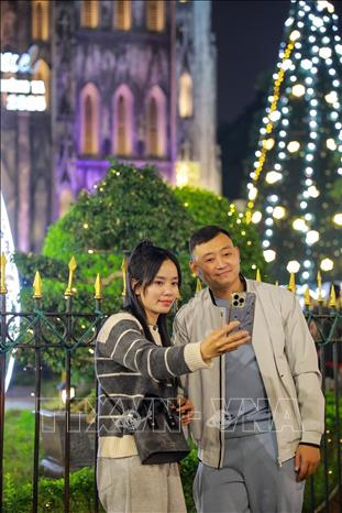 Người dân và du khách lưu lại khoảnh khắc trước Giáng sinh tại Nhà thờ lớn (phường Hoàn Kiếm). Ảnh: Khánh Hoà - TTXVN