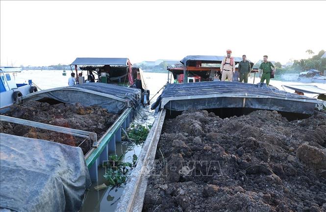 Đội Cảnh sát đường thủy số 2 (Phòng Cảnh sát giao thông Công an tỉnh An Giang) phối hợp Công an xã Bình Hoà kiểm tra đất được vận chuyển trái phép trên các sà lan. Ảnh: TTXVN phát