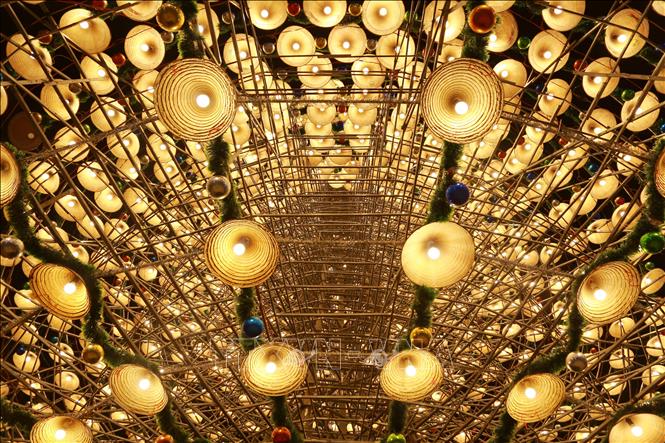 Cây thông được trang trí bằng chiều chiếc nón lá, bóng đèn, dây ki tuyến và quả châu tạo nên vẻ đẹp huyền bí. Ảnh: Lê Xuân-TTXVN
