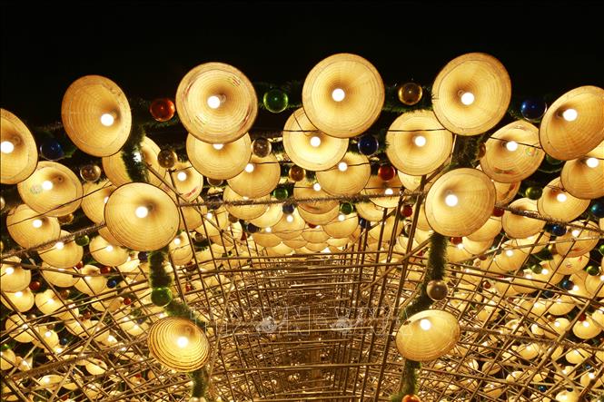 Cây thông được trang trí bằng chiều chiếc nón lá, bóng đèn, dây ki tuyến và quả châu tạo nên vẻ đẹp huyền bí. Ảnh: Lê Xuân-TTXVN