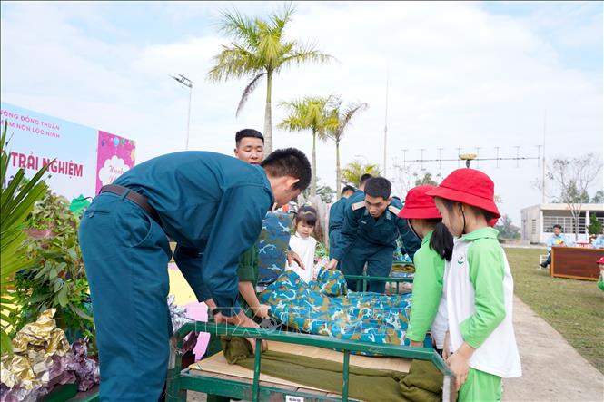 Các cán bộ, chiến sỹ Trạm Rađa 56, Trung đoàn 290, Sư đoàn 375, Quân chủng Phòng không không quân hướng dẫn các em học sinh cách gấp nội vụ. Ảnh: Thanh Thuỷ - TTXVN                                                              