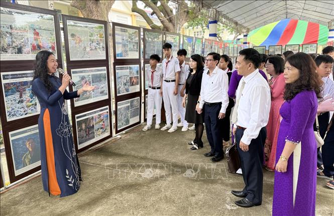 Đại biểu và học sinh tham quan, tìm hiểu ảnh, tư liệu tuyên truyền phòng, chống rác thải nhựa. Ảnh: Tường Quân - TTXVN