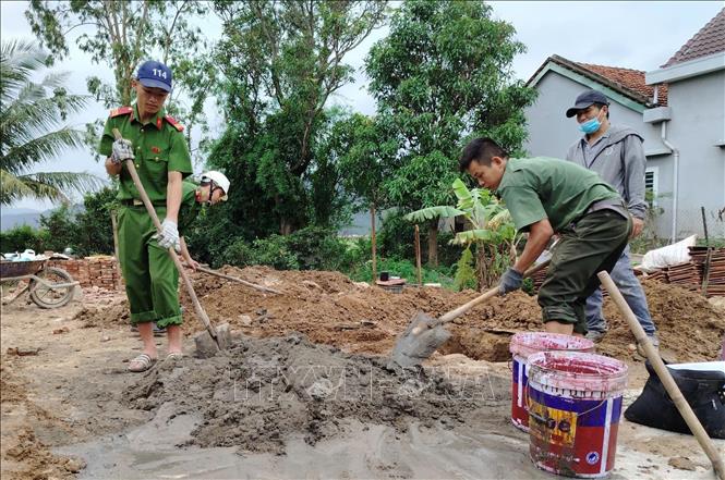 Cán bộ, chiến sĩ Công an thực hiện các phần việc xây sửa nhà hỗ trợ người dân phường Đông Hòa. Ảnh: Tường Quân - TTXVN