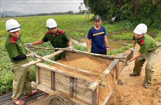 Chiến sĩ Công an tỉnh Đắk Lắk hỗ trợ người dân xa khu dân cư vận chuyển vật liệu xây dựng nhà ở mới sau lũ. Ảnh: Tường Quân - TTXVN