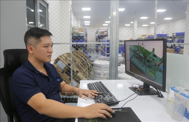 Kỹ sư Nguyễn Thái Hải với bản thiết kế máy làm lợi cho doanh nghiệp 1,6 tỷ đồng mỗi năm. Ảnh: Minh Thu - TTXVN