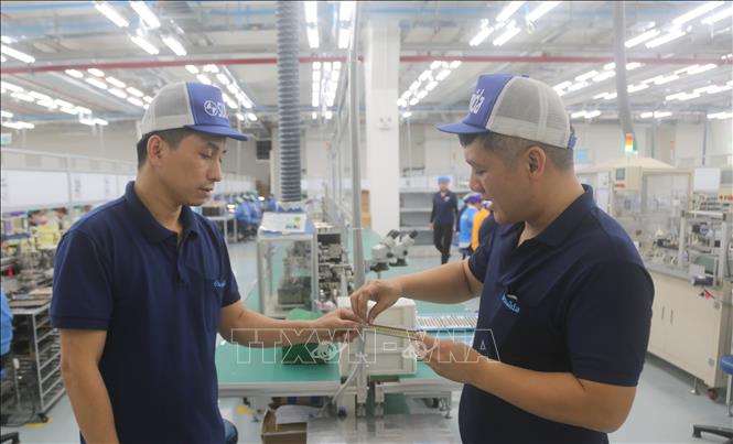 Các chi tiết máy được kỹ sư Nguyễn Thái Hải (phải) nghiên cứu để vận hành tối ưu hơn. Ảnh: Minh Thu - TTXVN