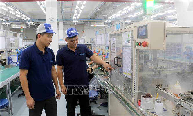 Kỹ sư Nguyễn Thái Hải (phải) cùng các đồng nghiệp xác nhận máy móc đã được đưa vào vận hành. Ảnh: Minh Thu- TTXVN