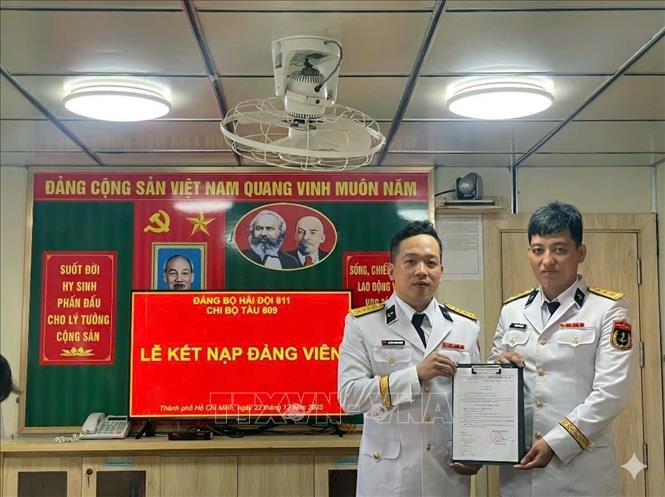 Đảng viên mới Nguyễn Văn Tiến (phải) nhận quyết định kết nạp Đảng. Ảnh: TTXVN phát 