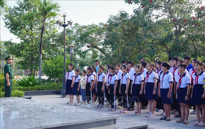Các em học sinh tưởng niệm các liệt sĩ tại bia tưởng niệm liệt sĩ. Ảnh: TTXVN phát