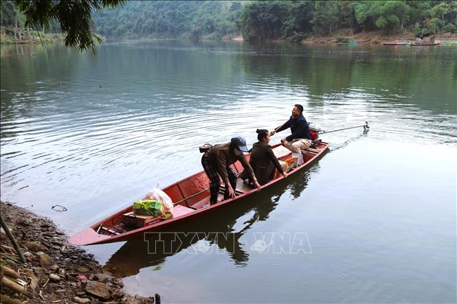 Người phụ nữ lúi húi giữa thăng bằng lúc thuyền máy chòng chành rời bến. Ảnh: Xuân Tiến - TTXVN 