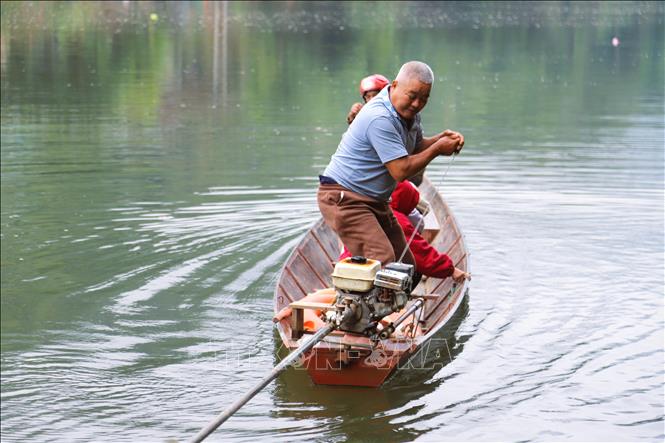 Chủ phương tiện thuyền máy khởi động máy trong tư thế chông chênh trên con thuyền sắt có kích thước nhỏ. Ảnh: Xuân Tiến - TTXVN 