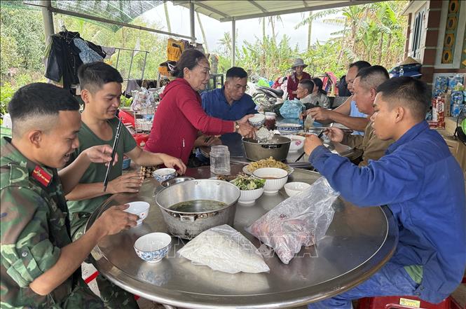 Chiến sĩ Quân khu 5 cùng người dân xã Hòa Thịnh ăn uống, nghỉ ngơi sau một ngày làm việc vất vả. Ảnh: Tường Quân - TTXVN
