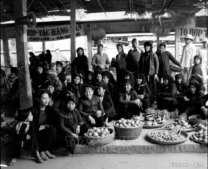 Bà con tiểu thương chợ Lớn Hải Dương theo dõi qua đài phát thanh về buổi họp Quốc hội thông qua Hiến pháp mới (31/12/1959). Ảnh: TTXVN