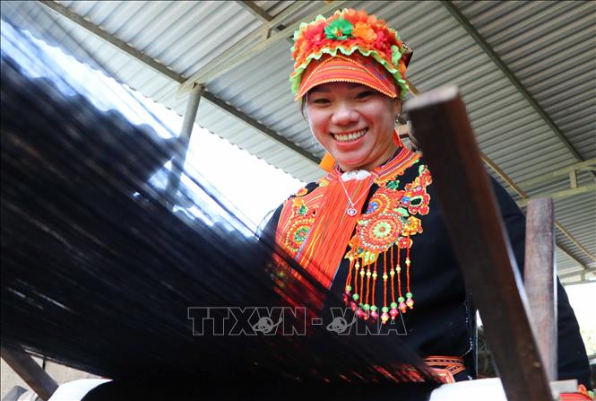 A Dao woman happily spins the yarn. VNA Photo: Nguyễn Oanh