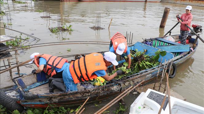 Các lực lượng, tình nguyện viên tham gia thu gom rác, lục bình trên rạch Khai Luông sau lễ phát động. Ảnh: Hồng Thái - TTXVN