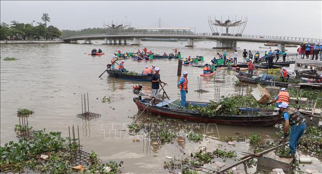 Các lực lượng, tình nguyện viên tham gia thu gom rác, lục bình trên rạch Khai Luông sau lễ phát động. Ảnh: Hồng Thái - TTXVN