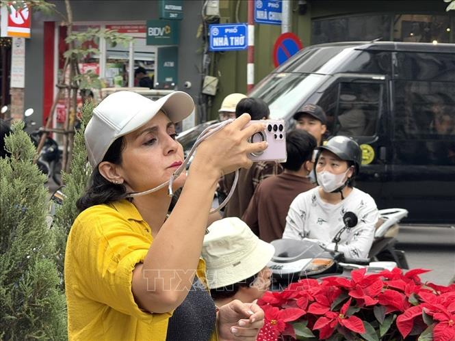Hòa chung không khí Giáng sinh, du khách nước ngoài chọn Nhà thờ lớn, phố Nhà Thờ (Hà Nội) là nơi chụp ảnh lưu niệm. Ảnh: Quốc Lũy - TXVN