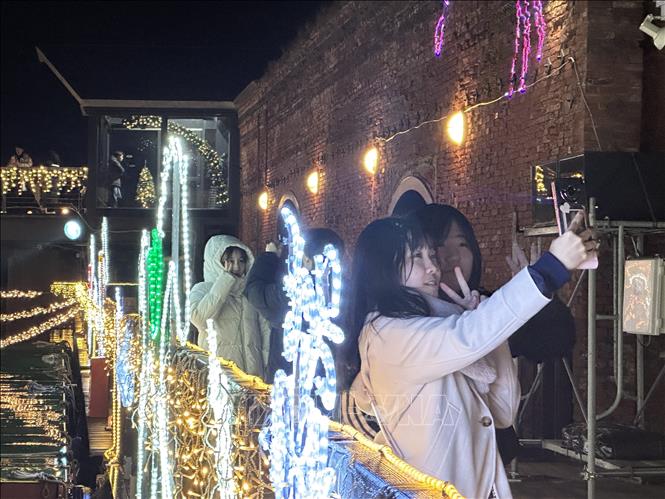 Thiếu nữ Nhật Bản ghi lại kỷ niệm Giáng sinh 2025 tại Kanemori, nơi diễn ra Lễ hội Giáng Sinh Hakodate Christmas Fantasy. Ảnh: Nguyễn Tuyến – Pv TTXVN tại Nhật Bản