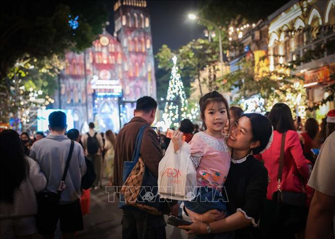 Người dân lưu lại khoảnh khắc đáng nhớ trong đêm Giáng sinh 2025 tại Nhà thờ Lớn. Ảnh: Hoàng Hiếu - TTXVN