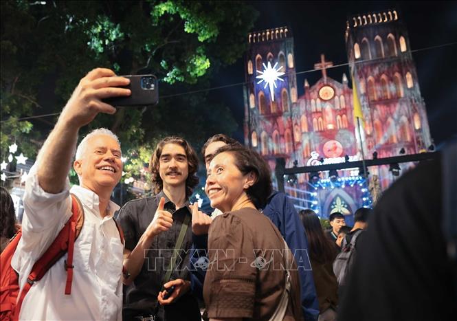 Du khách nước ngoài ghi lại khoảnh khắc chờ đón Giáng sinh 2025 tại quảng trường trước Nhà thờ Lớn. Ảnh: Hoàng Hiếu - TTXVN