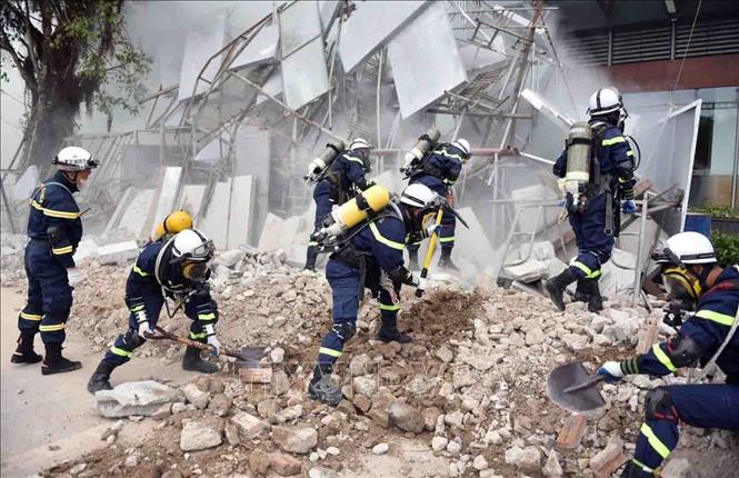 Lực lượng PCCC và CNCH sử dụng phương tiện chuyên dụng cứu nạn, cứu hộ khu vực cấu kiện sập đổ. Ảnh: TTXVN phát
