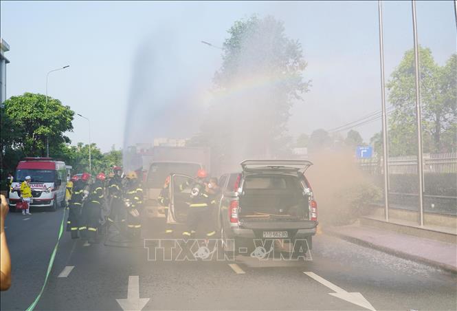 Lực lượng chức năng cứu người bị mắc kẹt trong xe và dập tắt đám cháy. Ảnh: Thu Hoài - TTXVN