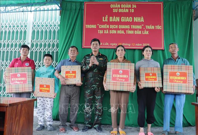 Thượng tá Đặng Thành Tuyên, Phó Chính ủy Sư đoàn 10, Quân đoàn 34 (Bộ Quốc phòng) tặng quà cho các hộ dân về nhà mới. Ảnh: Tường Quân - TTXVN