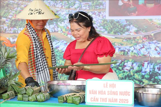 Khách du lịch trải nghiệm tự tay gói bánh lá Tét lá cẩm bằng lá dừa nước. Ảnh: Nguyễn Hằng - TTXVN