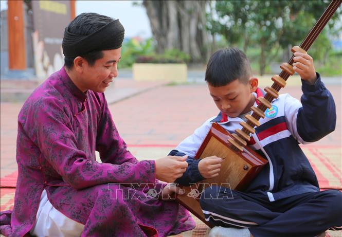 Nghệ nhân Ưu tú Tô Văn Tuyên, Chủ nhiệm Câu lạc bộ ca trù Đông Môn, hướng dẫn học sinh Trường Tiểu học Hòa Bình chơi đàn đáy. Ảnh: Minh Thu - TTXVN